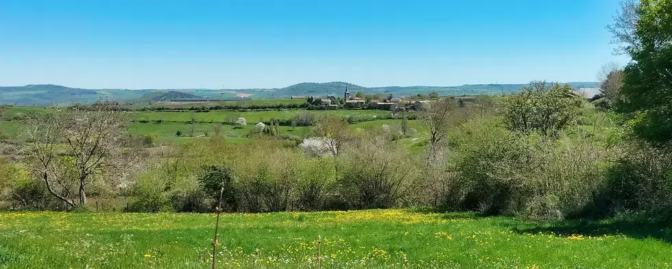 Au loin, la skyline du bourg de Chazeloux, dominé par son église imposante